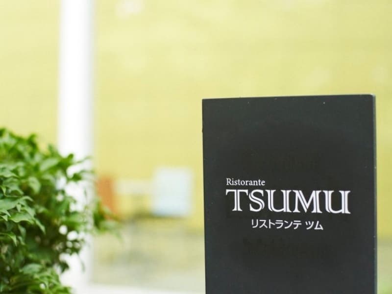 緑に映える「Ristorante TSUMU」の店舗看板。落ち着いたデザインの看板がゲストを上質な食の世界へと誘います。