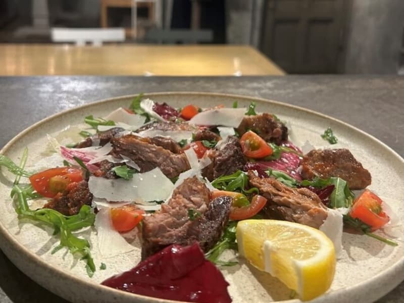 新鮮な野菜とレモンを添えた、見た目にも華やかな肉料理。素材の旨みを活かしたシェフこだわりの一皿です。