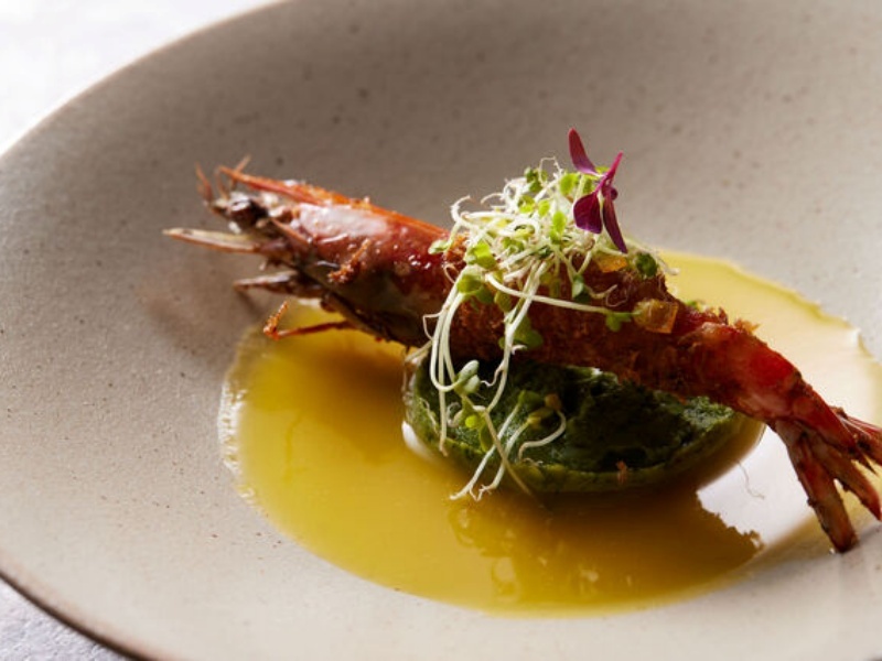 鮮やかなソースと彩り豊かな野菜を添えた海老の一皿。見た目にも美しく、素材の旨みが際立ちます。