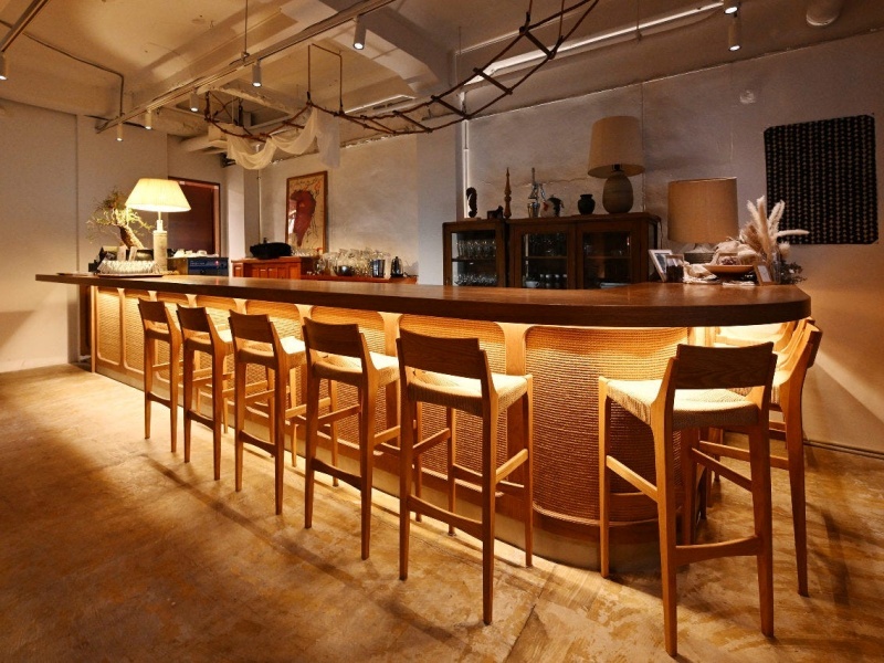 木のカウンターとバースツールが並ぶ洗練されたバーカウンター