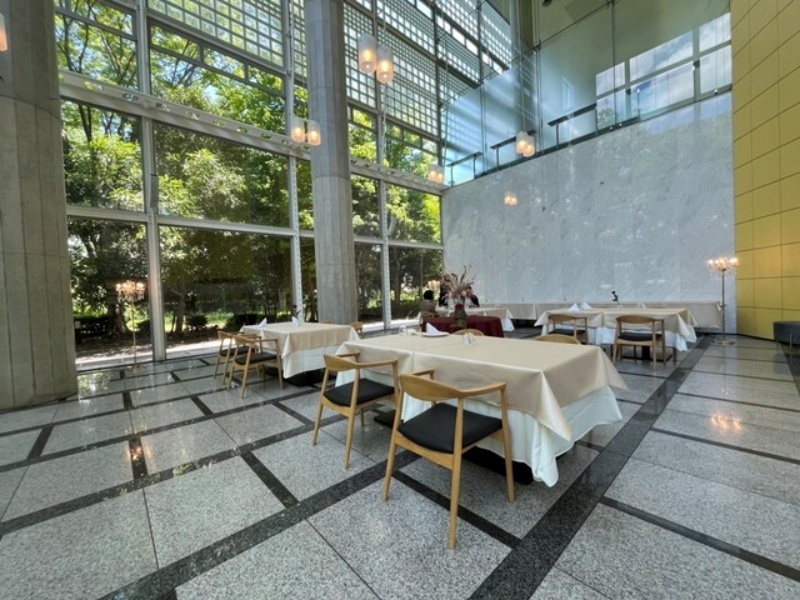 天井まで広がるガラス張りの開放的な会場全景。緑を望む明るい空間は、立食・着席どちらのスタイルにも対応し、華やかなパーティーシーンを引き立てます。(着席は50名様迄です。別途設営料(15000円)が発生いたします。)